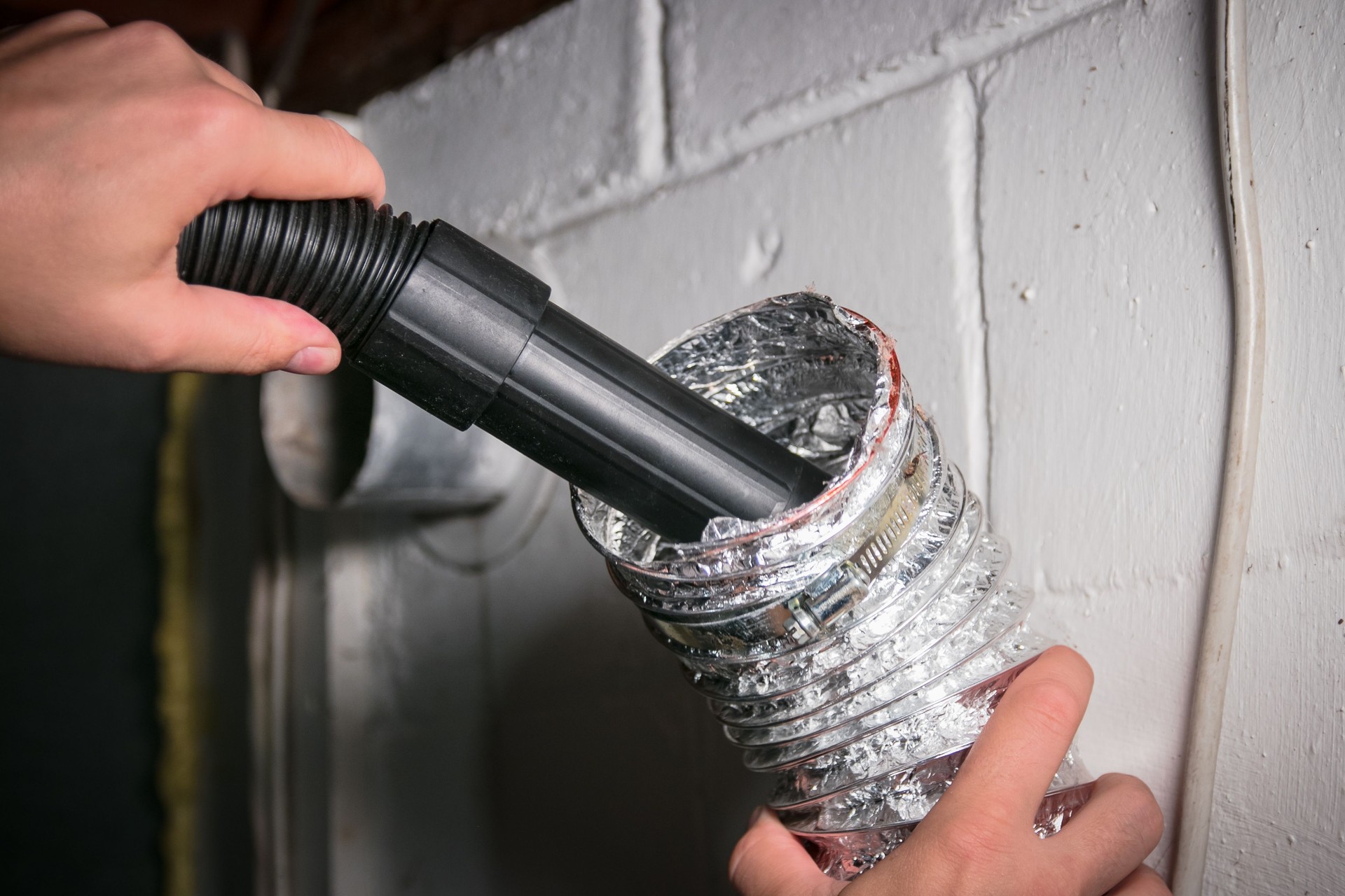Vacuum cleaning a flexible aluminum dryer vent hose, to remove lint and prevent fire hazard.